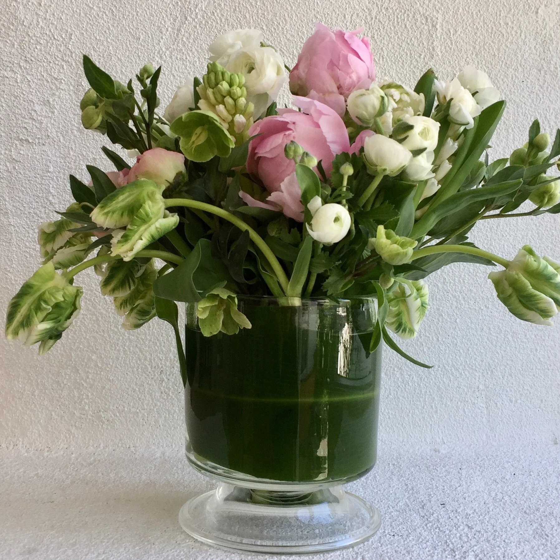 Garden roses and parrot tulips in leaf-lined glass